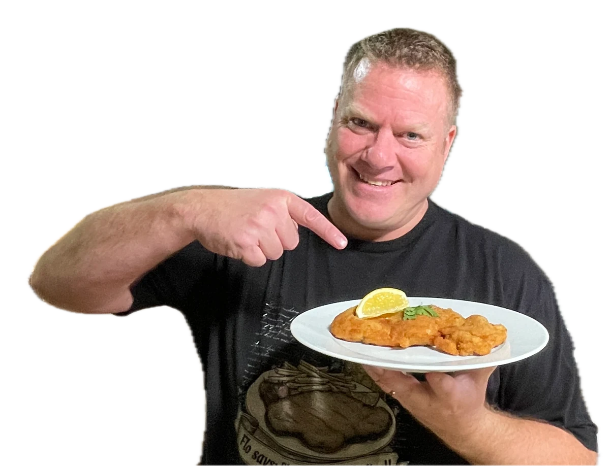 Flo, smiling and pointing at a plate of schnitzel